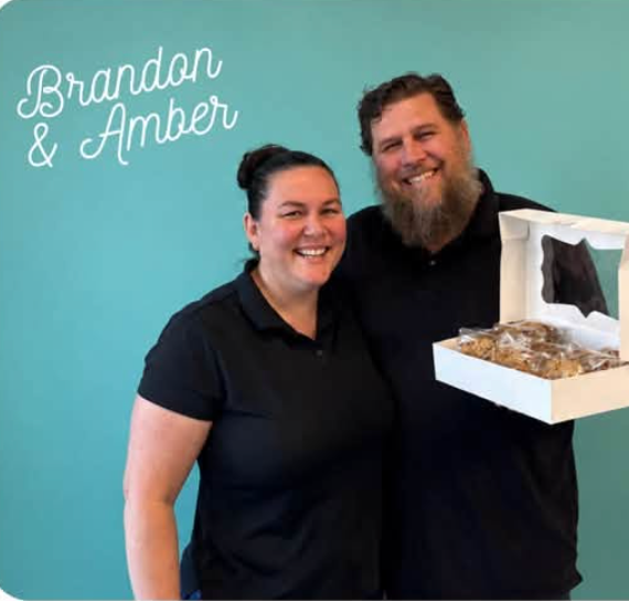 Brandon and Amber of Wonder Wisps Creations holding a box of fresh-baked treats